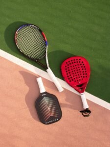 Tennis, padel, and pickleball rackets on a vibrant multi-colored court.